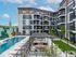 Modern apartment complex courtyard with a large swimming pool, vibrant mural, and stylish outdoor seating area, surrounded by lush greenery and architectural charm.