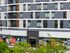 Modern multi-story building with sleek exterior design, featuring available retail spaces for lease and a stylish entrance labeled Ophelia among lush greenery.