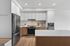 Contemporary open-plan kitchen with sleek white cabinetry, stylish hardwood flooring, and modern stainless steel appliances under elegant recessed lighting.