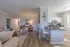Elegant open-plan living space with modern kitchen, cozy seating area, and stylish decor, featuring warm wood flooring and natural light.