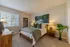 Bright and inviting bedroom with cozy decor, featuring a plush bed, elegant artwork, and large window with natural light.