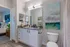 Modern bathroom with elegant vanity, large mirror, and stylish artwork, adjacent to a cozy bedroom.