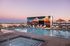 Exquisite rooftop pool area at sunset with vibrant mural, sun loungers, and panoramic city views.