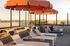 Inviting rooftop terrace with elegant lounge chairs and vibrant orange umbrellas, offering breathtaking sunset views.