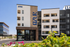 Modern apartment complex with contemporary design featuring 'AZUR' signage and colorful landscape, promoting vibrant blue sky living.