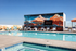 Vibrant rooftop pool area with stylish sun loungers, colorful mural, and stunning open sky views.