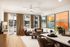 Modern living room with cozy brown sofa, elegant coffee table, and vibrant wall art, leading to a bright balcony view with floor-to-ceiling windows.