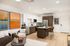 Modern open-concept living space featuring sleek kitchen with island seating, vibrant artwork, and cozy seating area.