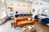 Chic apartment lounge with a modern leather sofa, vibrant blue chairs, and a sleek coffee bar, creating a welcoming and stylish ambiance.