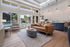 Modern living area with elegant decor, featuring a sleek leather sofa, chic lighting, and large windows offering a poolside view.