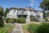 Charming two-story apartment building with private balconies and lush landscaping under a clear blue sky.