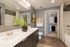 Modern bathroom with sleek double sinks, elegant mirror, vibrant plant decor, and a convenient walk-in closet.