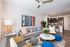 Contemporary open-plan living area with stylish decor, vibrant artwork, and a modern kitchen with sleek appliances.