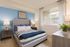 Bright and cozy bedroom with a plush gray bed, soft blue accents, elegant nightstands, and large window for natural light.