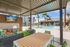 Luxurious outdoor lounge area featuring modern wicker seating, vibrant cushions, a sleek fire pit, and a sparkling swimming pool with palm tree accents.