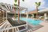 Luxurious outdoor pool area with modern loungers and palm trees, perfect for relaxation and entertainment.
