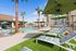 Luxurious outdoor pool area featuring palm trees, chic lounge chairs, and vibrant green umbrellas, perfect for relaxation.