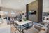 Modern living space featuring stylish seating, a large flat-screen TV, and a chic open-concept kitchen with unique lighting fixtures.