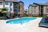 Elegant apartment complex featuring a refreshing outdoor swimming pool with sun loungers, stylish brick and siding exterior, and inviting balconies.