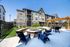 Charming apartment complex exterior featuring stone accents, spacious balconies, and a beautifully landscaped courtyard with cozy fire pit and stylish seating.