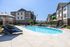 Inviting apartment complex featuring a sparkling outdoor pool, sun loungers, and umbrella-shaded relaxing areas.