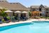 Luxurious apartment complex featuring a sparkling pool with elegant loungers and shaded umbrellas, perfect for relaxation and leisure.
