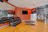Modern gym space featuring bright red accents, mirrored wall, free weights, and sleek wooden flooring.