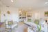 Bright and inviting living area with modern decor, featuring a cozy sofa, stylish armchair, and an open kitchen with bar seating.