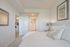 Inviting bedroom with elegant interior design, featuring plush bedding, a stylish lamp, and modern decor, offering a cozy retreat.