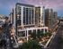 Modern urban apartment complex with sleek architecture, featuring floor-to-ceiling windows and rooftop amenities, set against a vibrant cityscape.