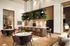 Modern open-concept living area with chic bar-style kitchen, elegant seating, and lush greenery in a luxurious apartment.
