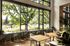 Bright and inviting communal space with floor-to-ceiling windows, lush greenery, and stylish seating, perfect for relaxation and social gatherings.