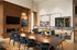 Elegant meeting room with a large wooden table, plush blue chairs, and ambient modern lighting, featuring impressive wall art and a sleek fireplace.
