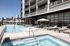 Luxurious urban apartment complex featuring a stunning pool area with stylish lounge chairs and downtown city views.