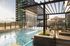 Luxurious rooftop pool with cascading waterfall feature and stylish loungers alongside modern high-rise apartment buildings.