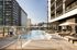 Luxurious rooftop swimming pool surrounded by modern high-rise apartments, offering stylish sun loungers and shaded seating areas.