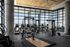 Modern gym with panoramic city views featuring state-of-the-art fitness equipment and sleek interior design.