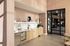 Elegant kitchen area with modern wooden cabinets, sleek marble countertop, and artistic decor, bathed in natural sunlight with a view of a stylish interior space.