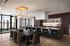 Luxurious open-plan kitchen and dining area with modern lighting, elegant furnishings, and floor-to-ceiling windows offering stunning city views.