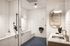 Modern pet washing station featuring sleek black shower fittings, elegant white tiles, and a convenient countertop sink with stylish lighting.