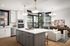 Elegant open-concept kitchen and living area with modern lighting, sleek white cabinetry, and large windows offering a bright and airy ambiance.