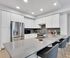 Modern kitchen with sleek white cabinets, stainless steel appliances, elegant countertops, and cozy bar seating.