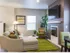 Side view of the living room with a green fuzzy rug underneath the beige couch, a TV on the wall above a modern fireplace