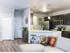 Kitchen with silver appliances such as refrigerator, microwave and stove top. Half circular island with granite counter top. Light brown hardwood floor with dark brown cabinets