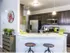 Side view of the kitchen with two bar stools against the half circular counter top. Two hanging lights