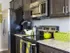 Dark cabinets. granite counter top, with silver appliances. A bright green basket and kettle pot