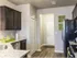 Kitchen view with light brown hardwood floors, two white doors against a light grey wall color