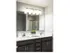Double sinks in the bathroom with dark wood cabinets underneath. Long mirror that stretches across the counter top.