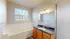 Bright and modern bathroom featuring a luxurious bathtub, elegant wooden cabinetry, and large vanity mirror, perfect for relaxation and comfort.