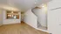 Bright and inviting open-concept living area featuring sleek wood flooring, a modern kitchen with stainless steel appliances, and elegant lighting fixtures, complete with a stylish staircase leading upstairs.